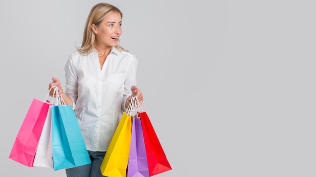 Woman holding many colorful shopping bags with copy space