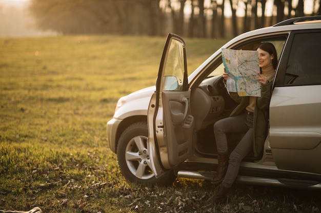 車のフルショットで地図を保持している女性