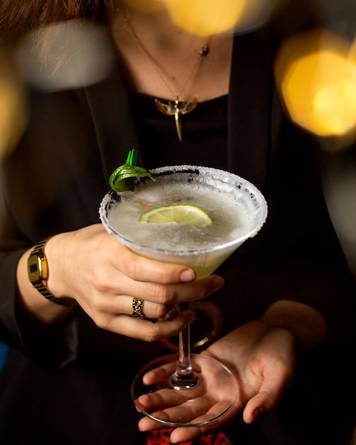 Woman holding a margarita glass garnished with lime