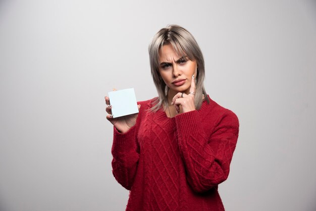 Woman holding memo pad and thinking about something.