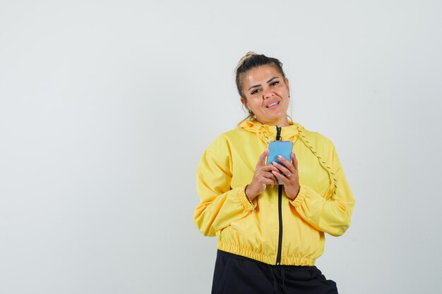 Woman holding mobile phone in sport suit and looking sensible , front view.
