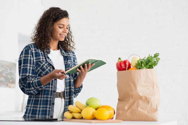 野菜の袋の横にあるノートを保持している女性