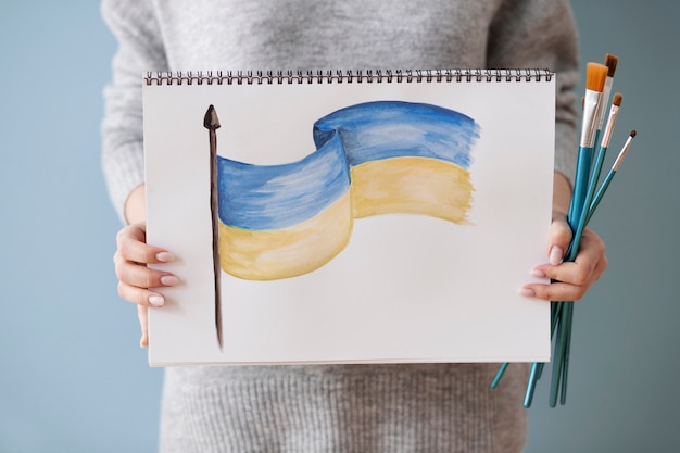 Woman holding notebook with ukrainian flag drawing