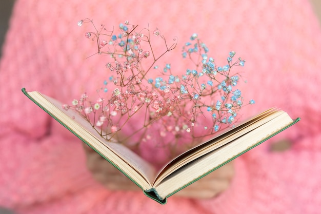 Foto gratuita donna che tiene un libro aperto con un mazzo di fiori secchi all'interno