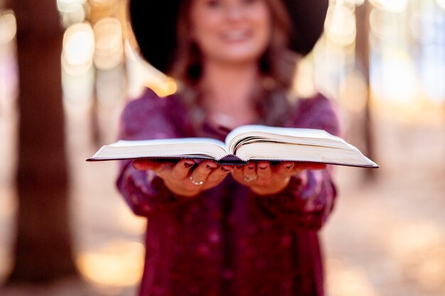 woman holding a opened book in the forest