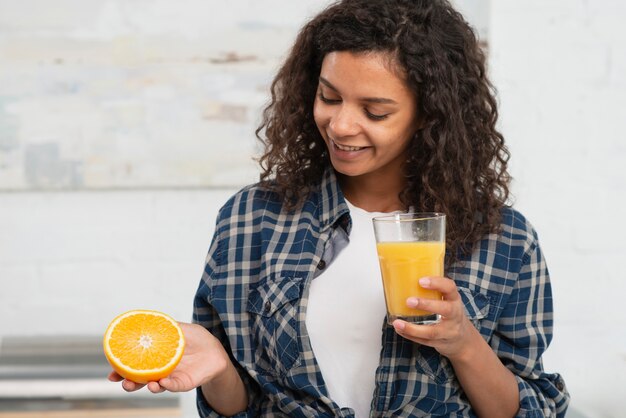 Woman holding a orange and a glass of juice