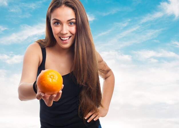 Foto gratuita donna in possesso di un arancio mentre sorridendo