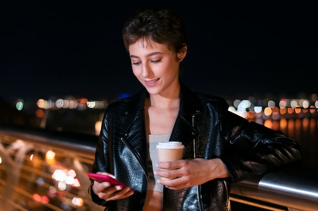 Woman holding phone and cup medium shot