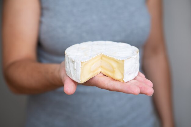 Woman holding piece of soft cheese on palm
