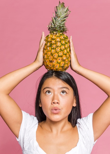 Free photo woman holding pineapple and looking at it