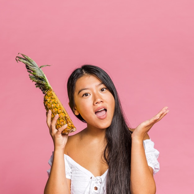 Женщина держит ананас и интересно