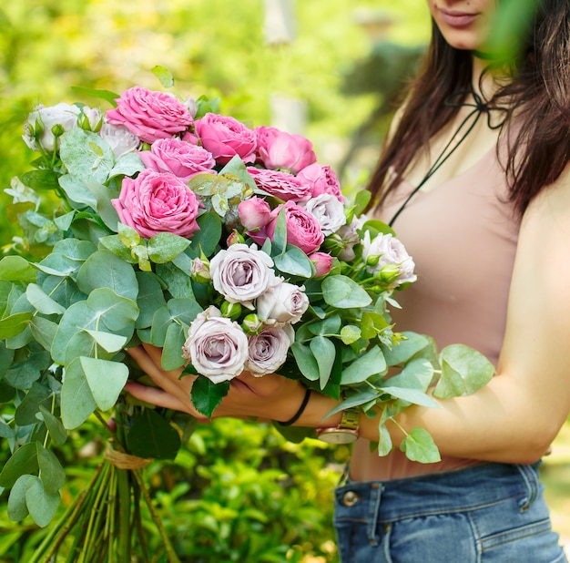 Woman holding pink roses bouquet with eucalypt leaves in the garden