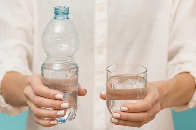 Woman holding a plastic bottle and a glass