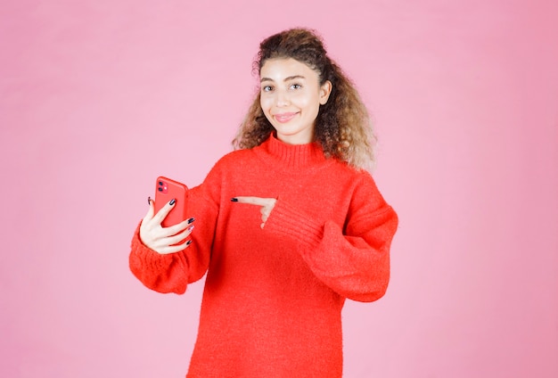 彼女の新しいブランドのスマートフォンを持って指さしている女性。