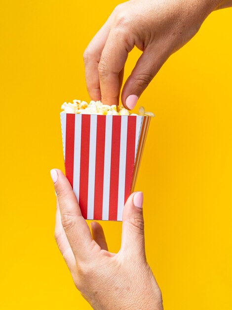 Woman holding popcorn box on yellow background