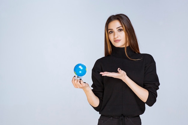 Foto gratuita donna che tiene e promuove un mini globo.