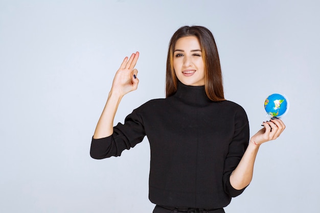 woman holding and promoting a mini globe.