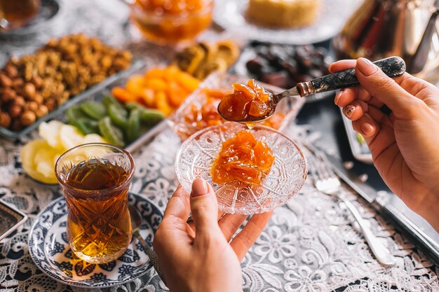Woman holding quince murabba in crystal saucer served with tea