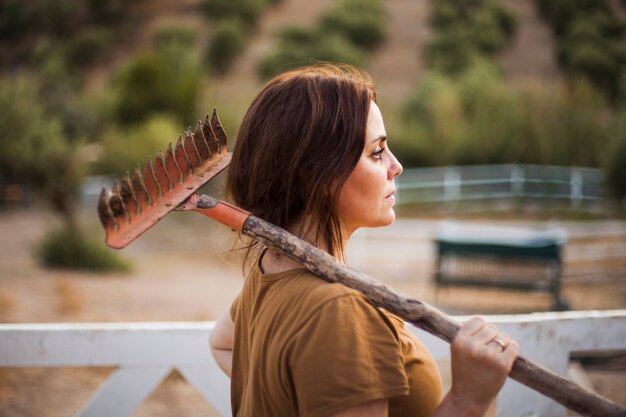 Woman holding rake on her shoulder