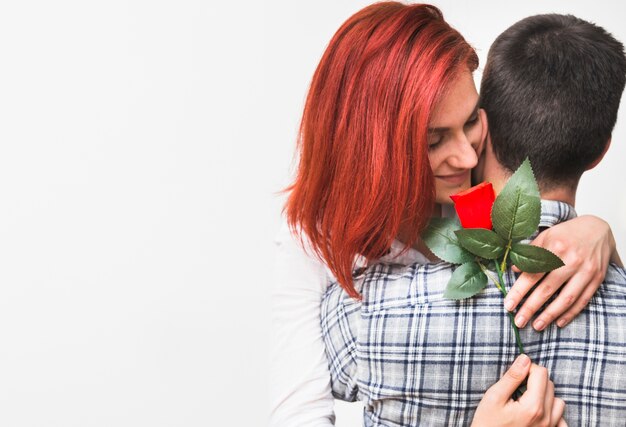 Woman holding red rose hugging her husband