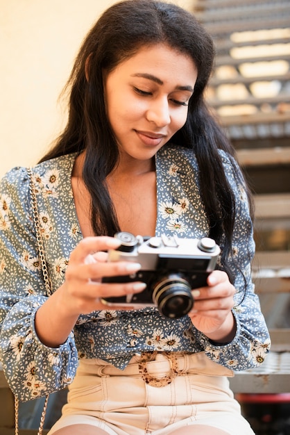 Woman holding a retro camera and looking at photos