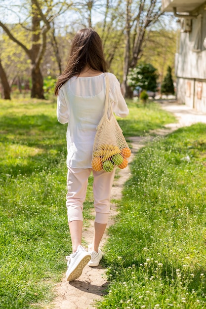 Woman holding reusable bag walking outside