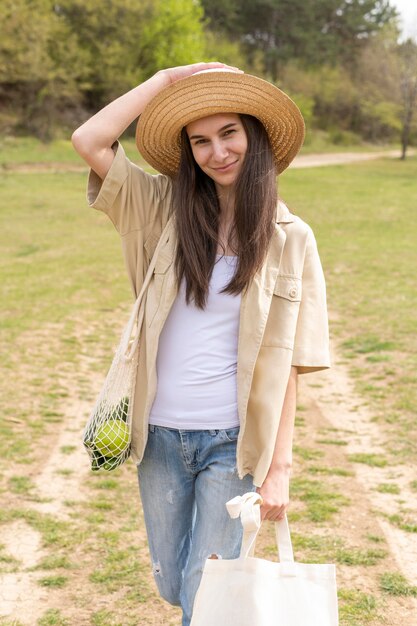 Foto gratuita donna che tiene le borse riutilizzabili in natura