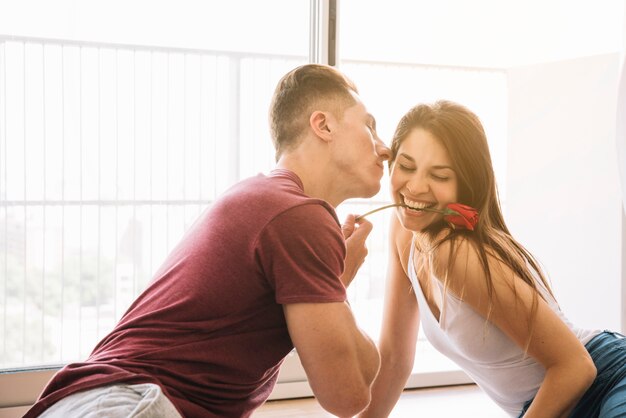 Woman holding rose branch in teeth in hand of man