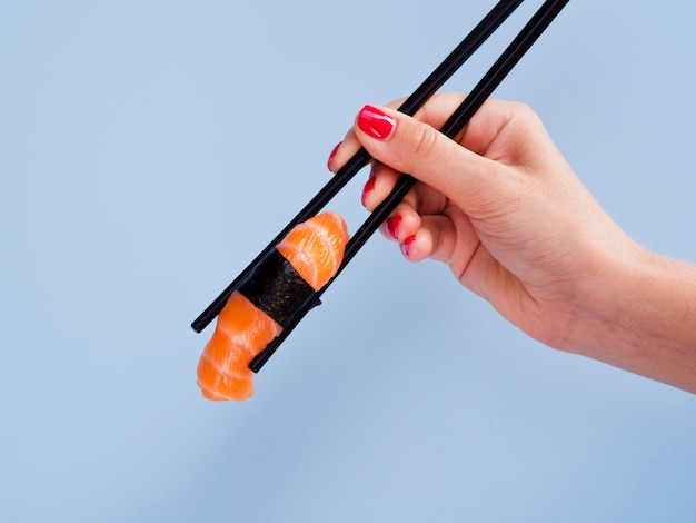 Woman holding a salmon sushi in chopsticks