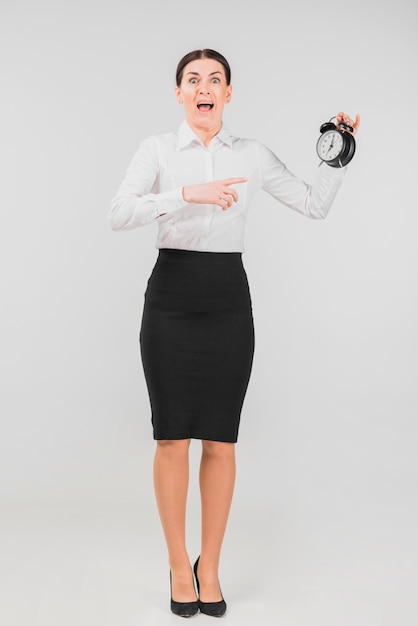 Free photo woman holding and scaring alarm clock