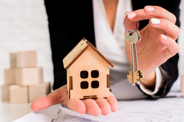 Woman holding a set of keys with wooden house