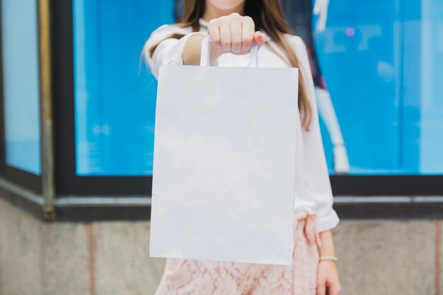 Woman holding shopping bag near shop window