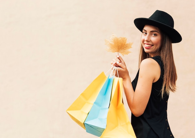 Woman holding shopping bags and a leaf with copy space