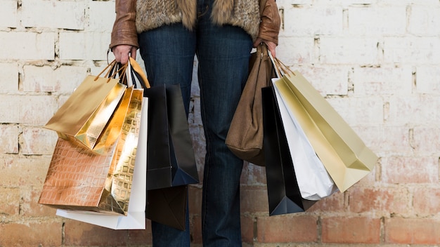 Woman holding shopping bags near wall