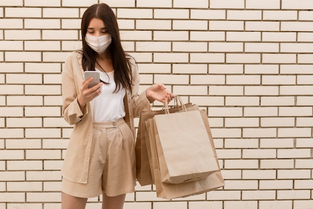 Woman holding shopping bags and wearing mask front view