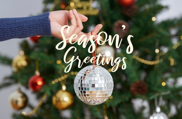 Woman holding silver christmas disco ball on christmas tree back