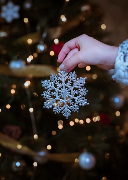 Woman holding silver snowflake in hand 