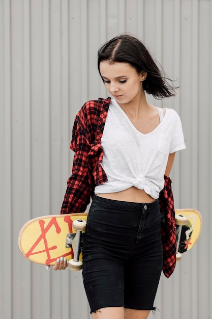 Woman holding skateboard behind back