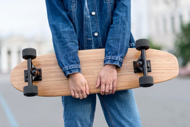 Foto gratuita donna che mantiene una vista frontale di skateboard