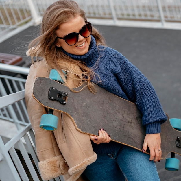 Foto gratuita donna che mantiene lo skateboard all'aperto