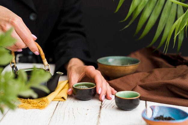 お茶と小さなカップを保持している女性