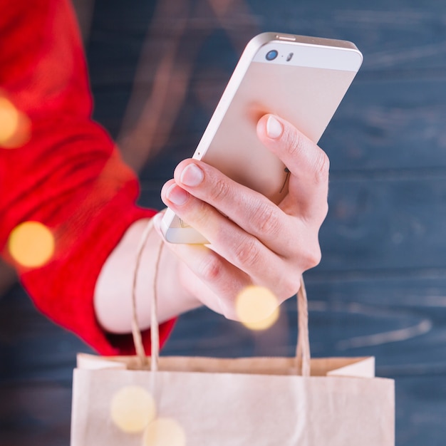 Woman holding smartphone and gift bag