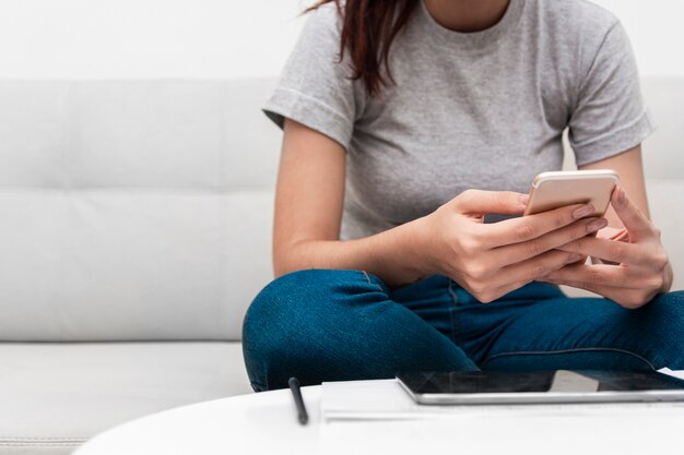 Woman holding smartphone while working at home