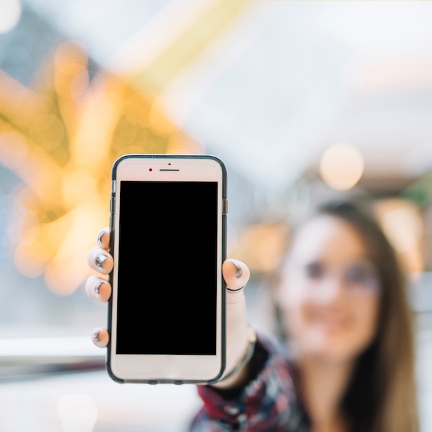 Woman holding smartphone with blank screen in hand 