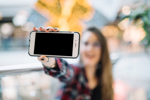 空白の画面を持つ女性持株スマートフォン