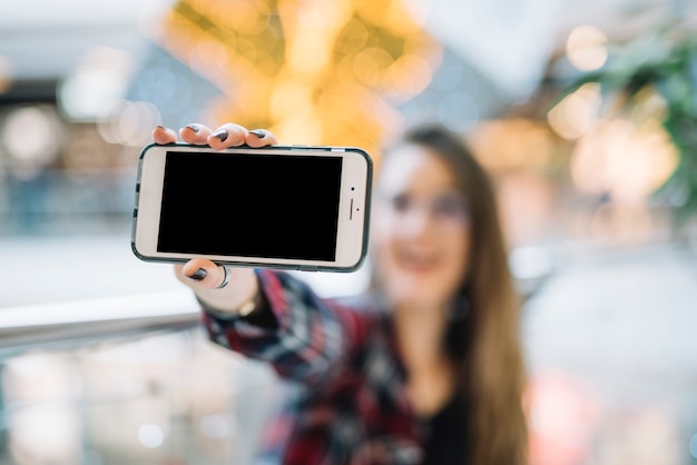 Woman holding smartphone with blank screen 