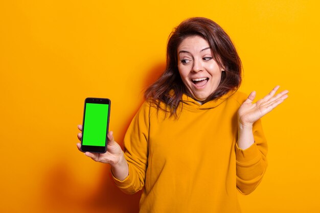 Woman holding smartphone with green screen