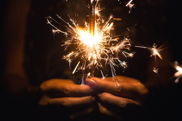 Woman holding sparkler, Bright festive Christmas sparkler.