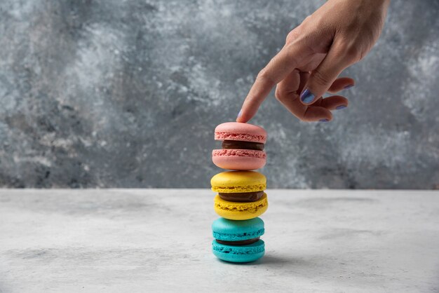 흰색 테이블에 macarons의 스택을 들고 여자입니다.