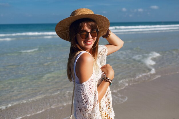 Woman holding straw bag and walking on the beach